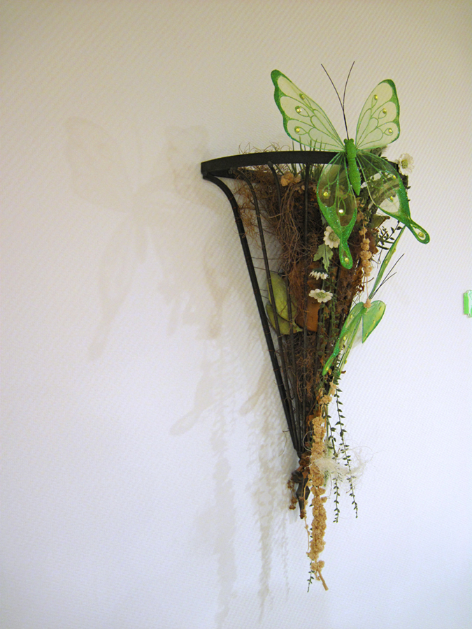 Detailaufnahme einer Wanddekoration aus getrockneten Pflanzen mit Schmetterling.